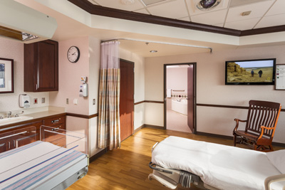 Image shows a private birthing suite at Aurora BayCare Medical Center, with a patient bed, in-room bassinet, rocking chair and TV.